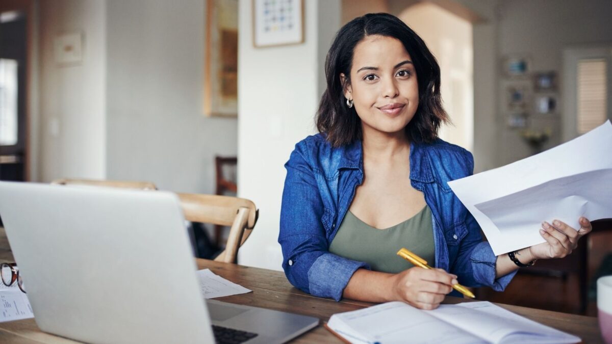 Ideas For Online Business From Home pictured is a female writing her business notes on a desk with a laptop